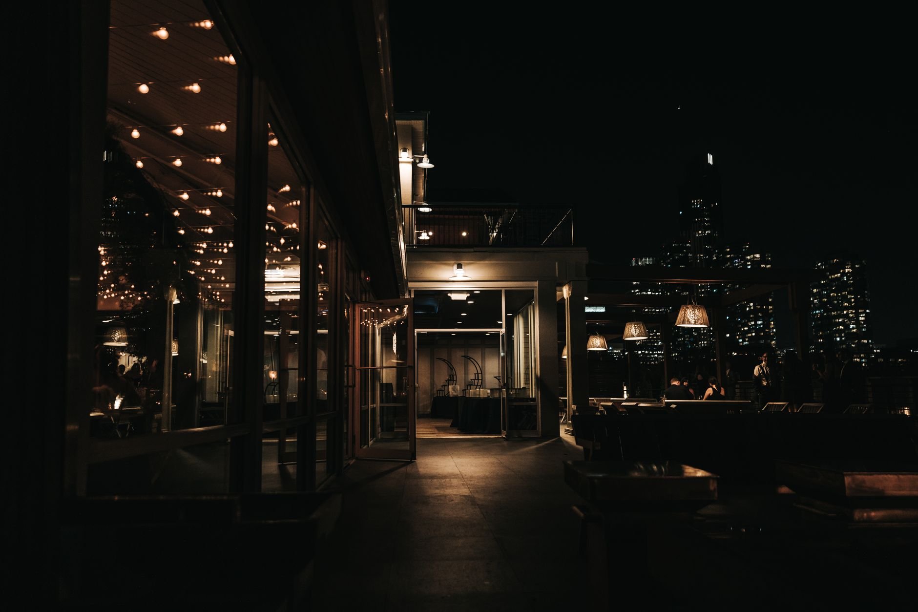 A stylish rooftop bar at night with a city skyline view and ambient lighting.