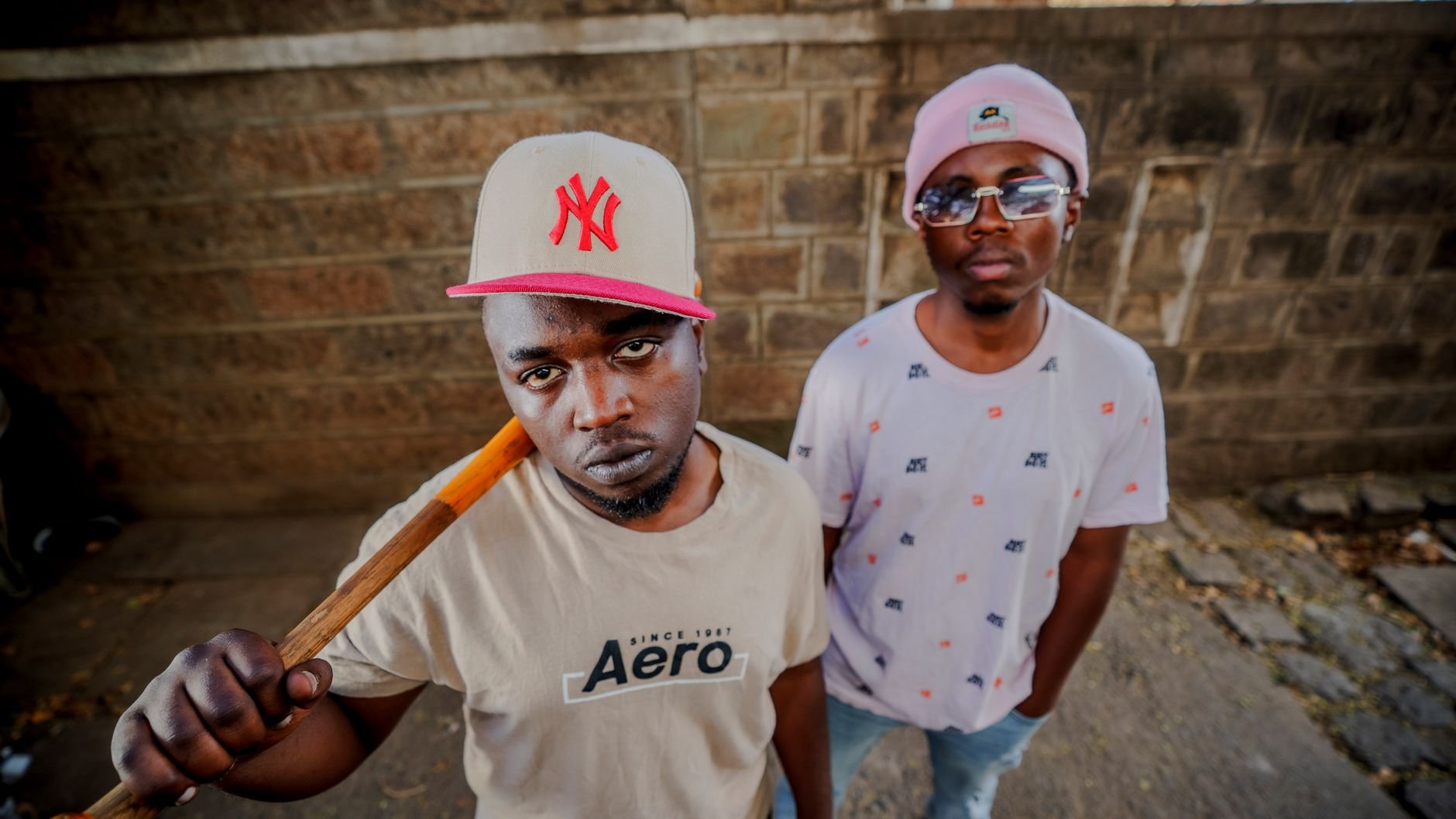 Stylish urban portrait of young men against a brick wall in Nairobi, Kenya.